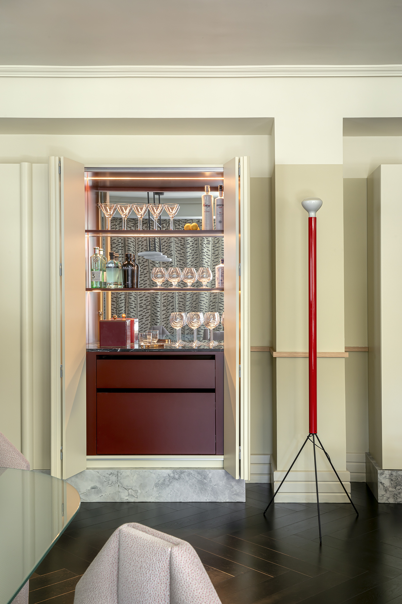 A series of interior shots depicting theatrically decorated spaces with bold lacquered red, chrome, patterned, and sculptural accents.