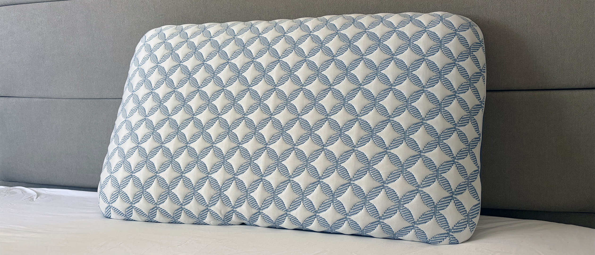 The Helix Cooling Memory Foam Pillow resting against the headboard of the bed in our reviewer's bedroom