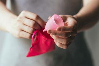 A woman holding a menstrual cup.