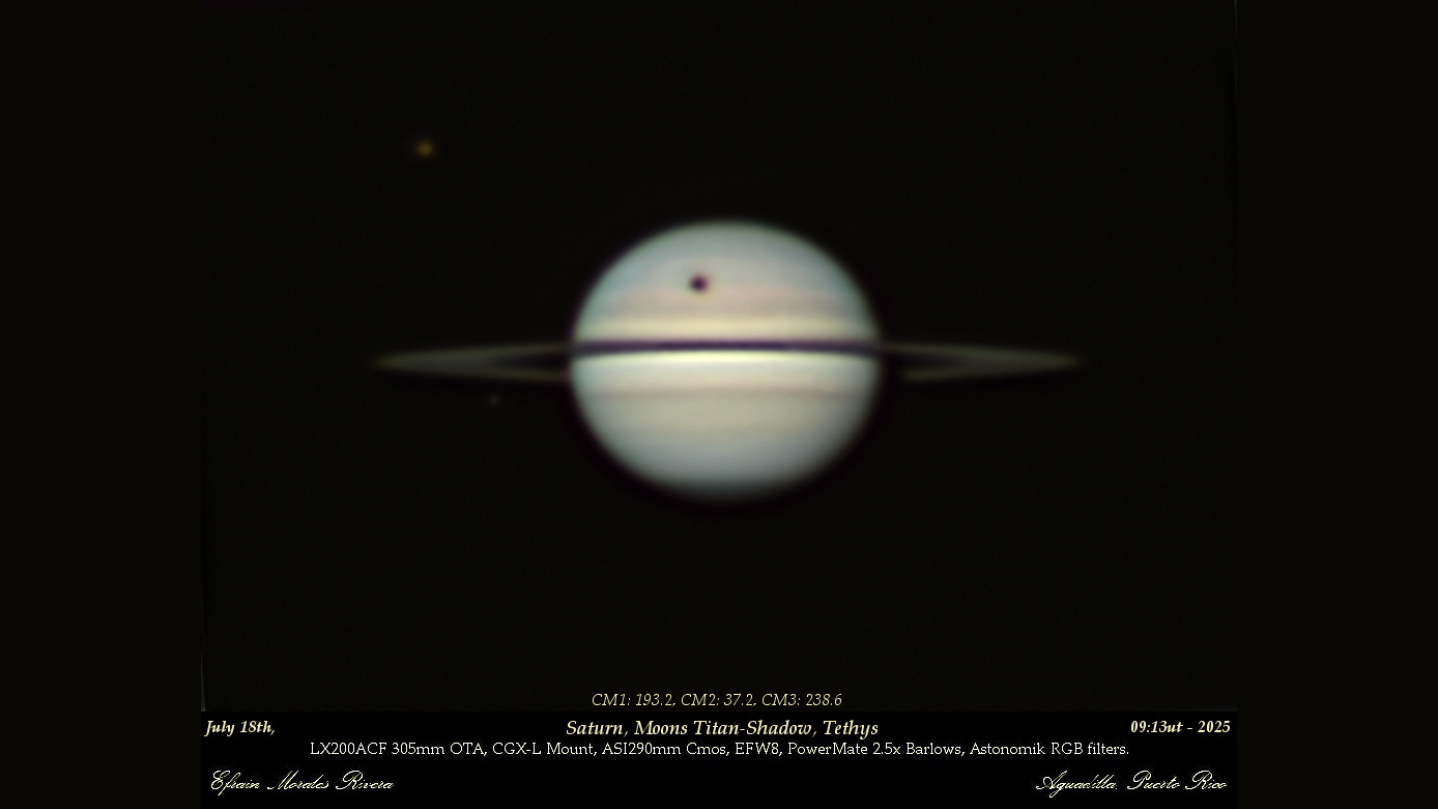 An image of the gas giant Saturn. The shadow of the large moon Titan is visible as a dark spot above its rings. Another Saturnian moon, Tethys, is visible to Saturn's upper left as a grey dot.