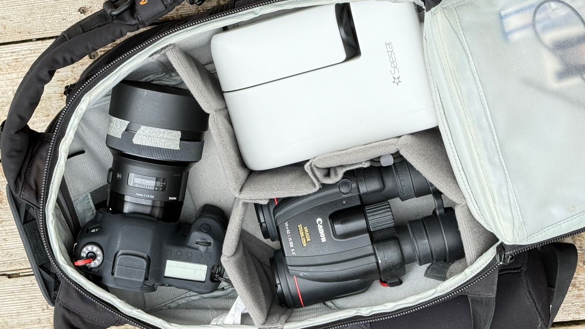 a backpack containing a smart telescope, a pair of binoculars and a camera.
