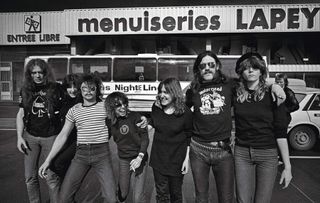 Motorhead and Girlscool on tour in 1979, posing in the street: L-R Eddie Clarke, Kim McAuliffe, Phil Taylor, Denise Dufort, Enid Williams, Lemmy, Kelly Johnson.