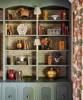 Bookshelves painted in light green with wallpaper behind