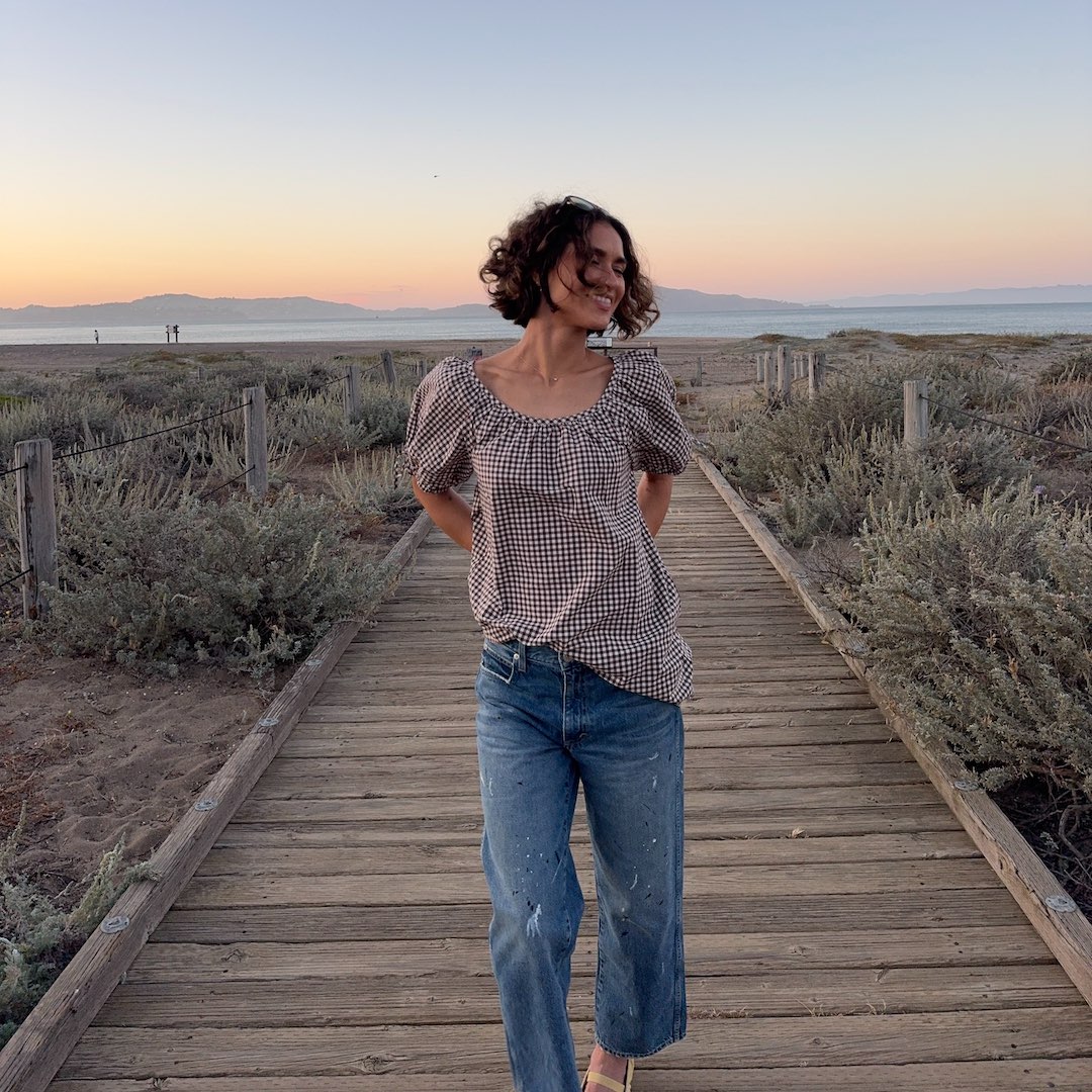 Caitlin Miyako wearing jeans and gingham blouse by the seafront at dusk - summer to autumn perfumes