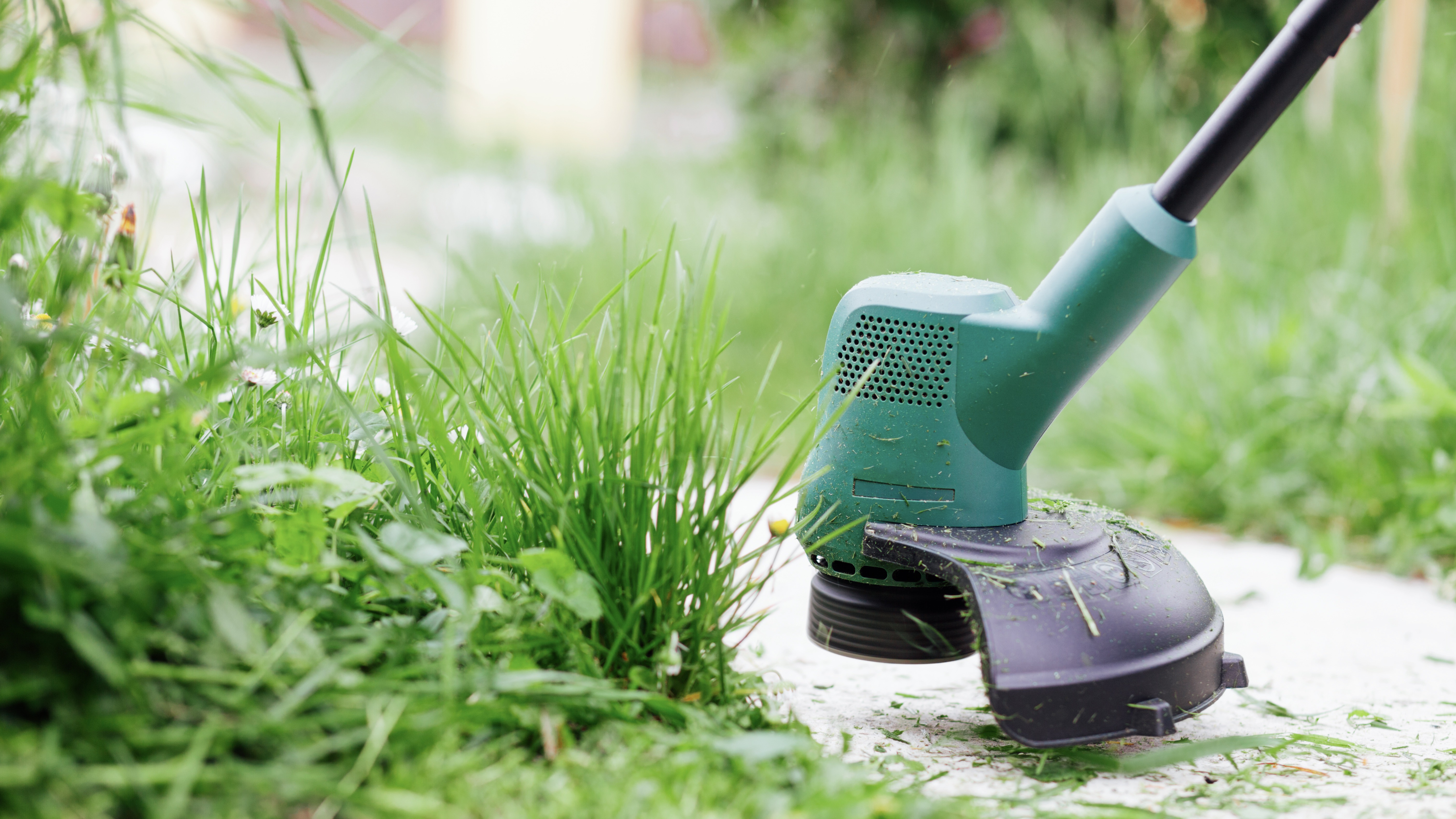 Edge trimmer cutting grass along a footpath