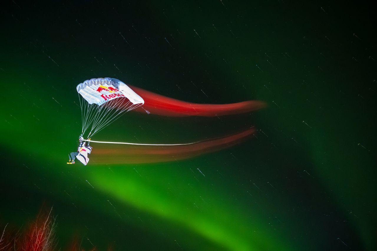 Photographer and skydiver Mike Brewer prepares to land under the northern lights
