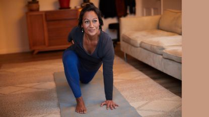Woman doing 15-minute Pilates workout on yoga mat in living room
