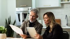 An older couple work on financial planning in their kitchen.
