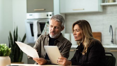An older couple work on financial planning in their kitchen.