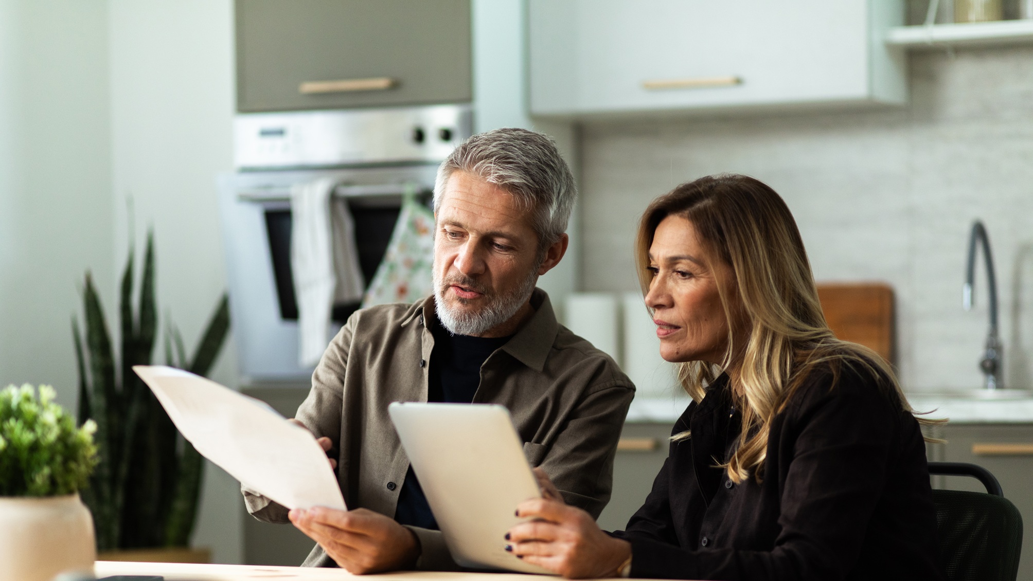 An older couple work on financial planning in their kitchen.