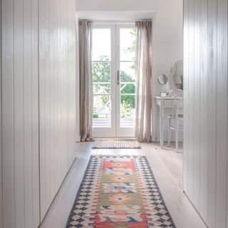 Hallway with built in cupboards and glass double doors at the end.