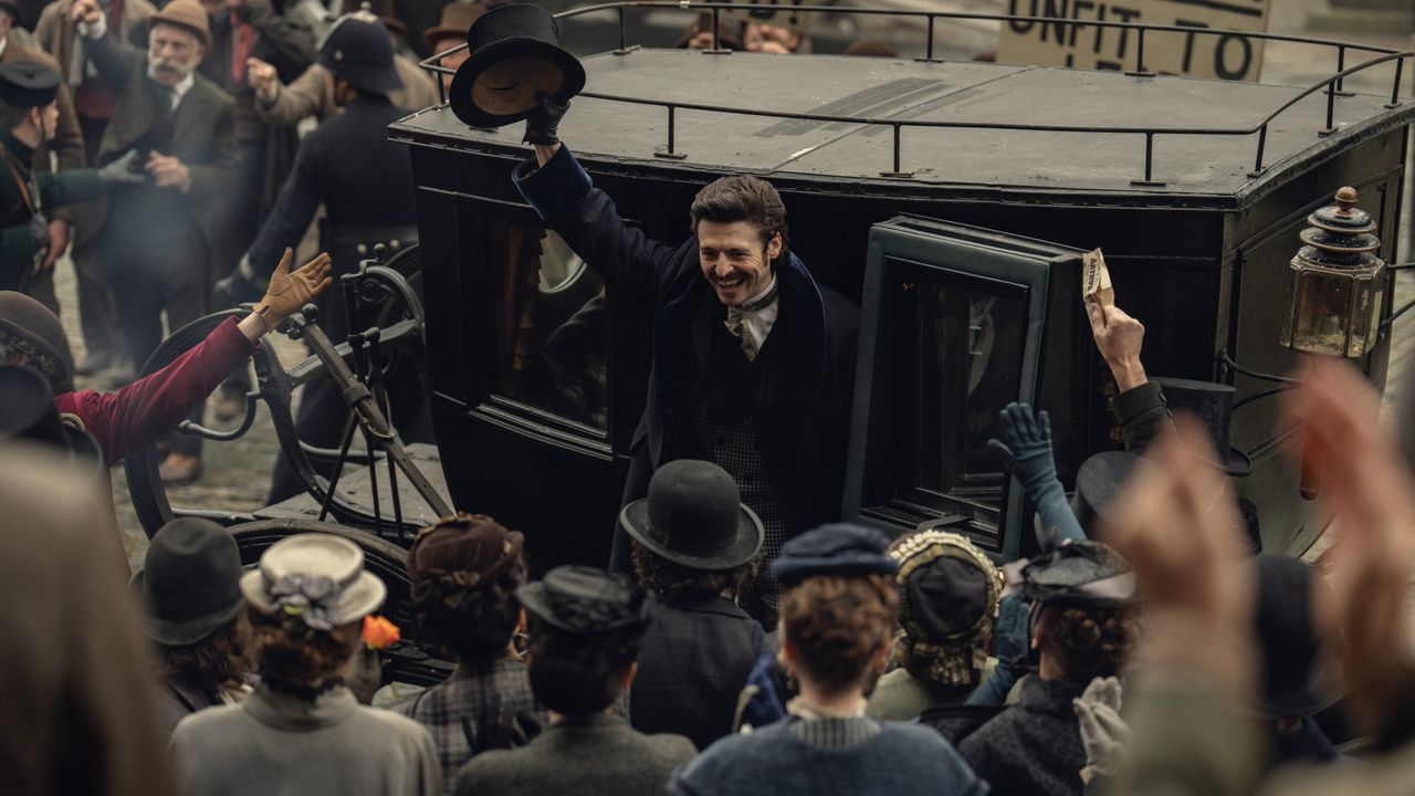 A first-look photo from Netflix's "House of Guinness", showing Anthony Boyle waving to a crowd as he steps out of a carriage