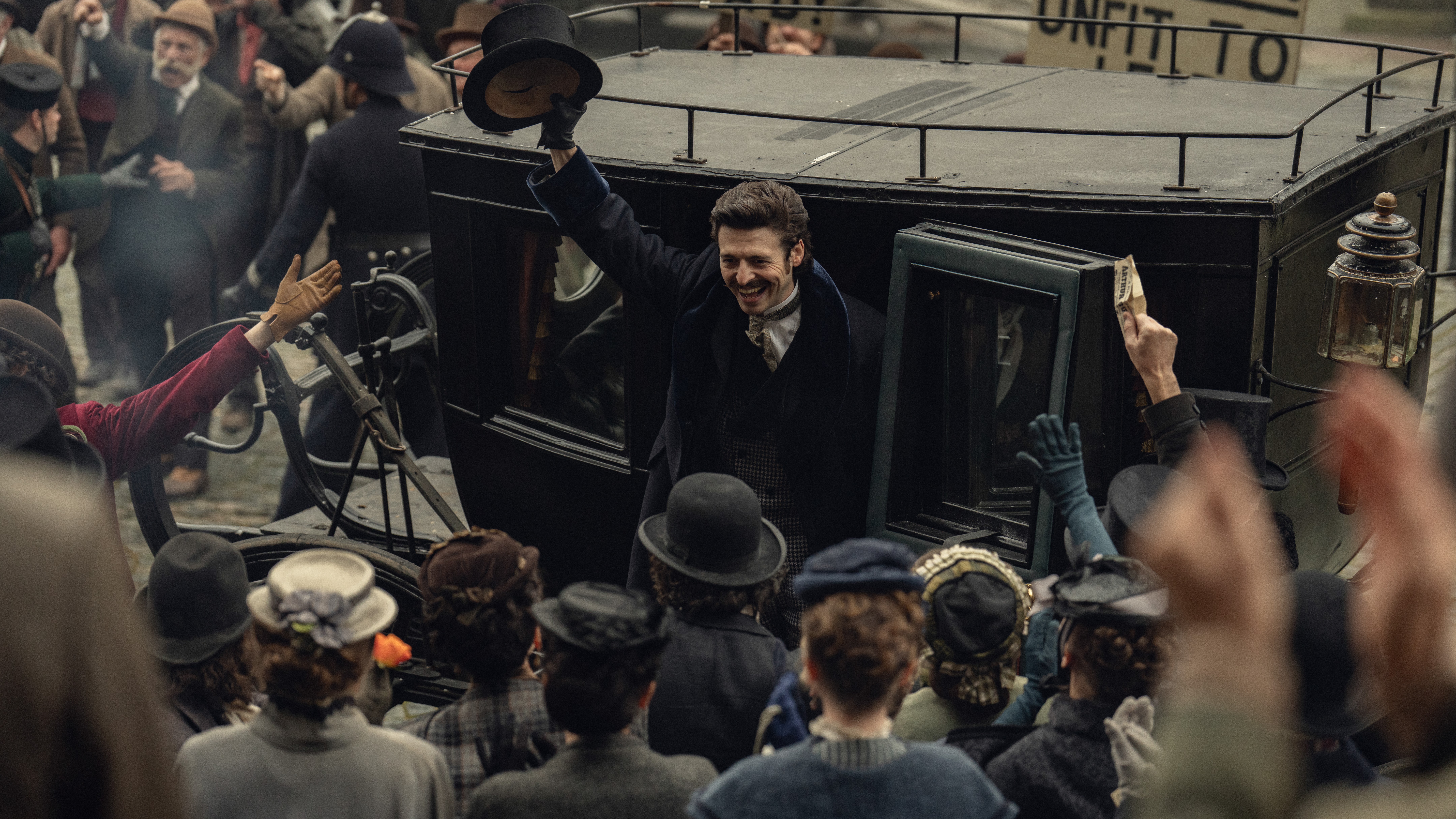 A first-look photo from Netflix's "House of Guinness", showing Anthony Boyle waving to a crowd as he steps out of a carriage