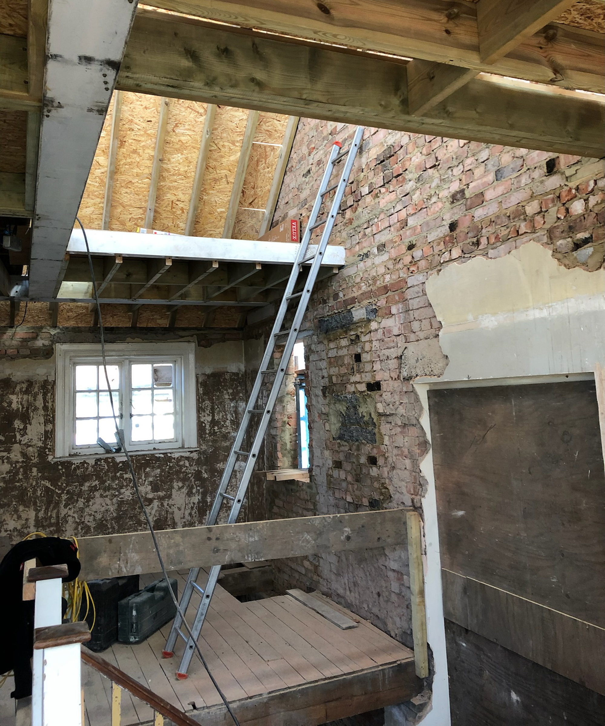 view of a ladder up against a brick wall with a wooden platform for a build