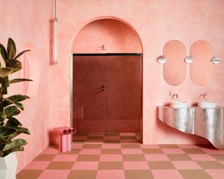 Pink bathroom with plastered walls, tiled floor and smoked glass shower screen