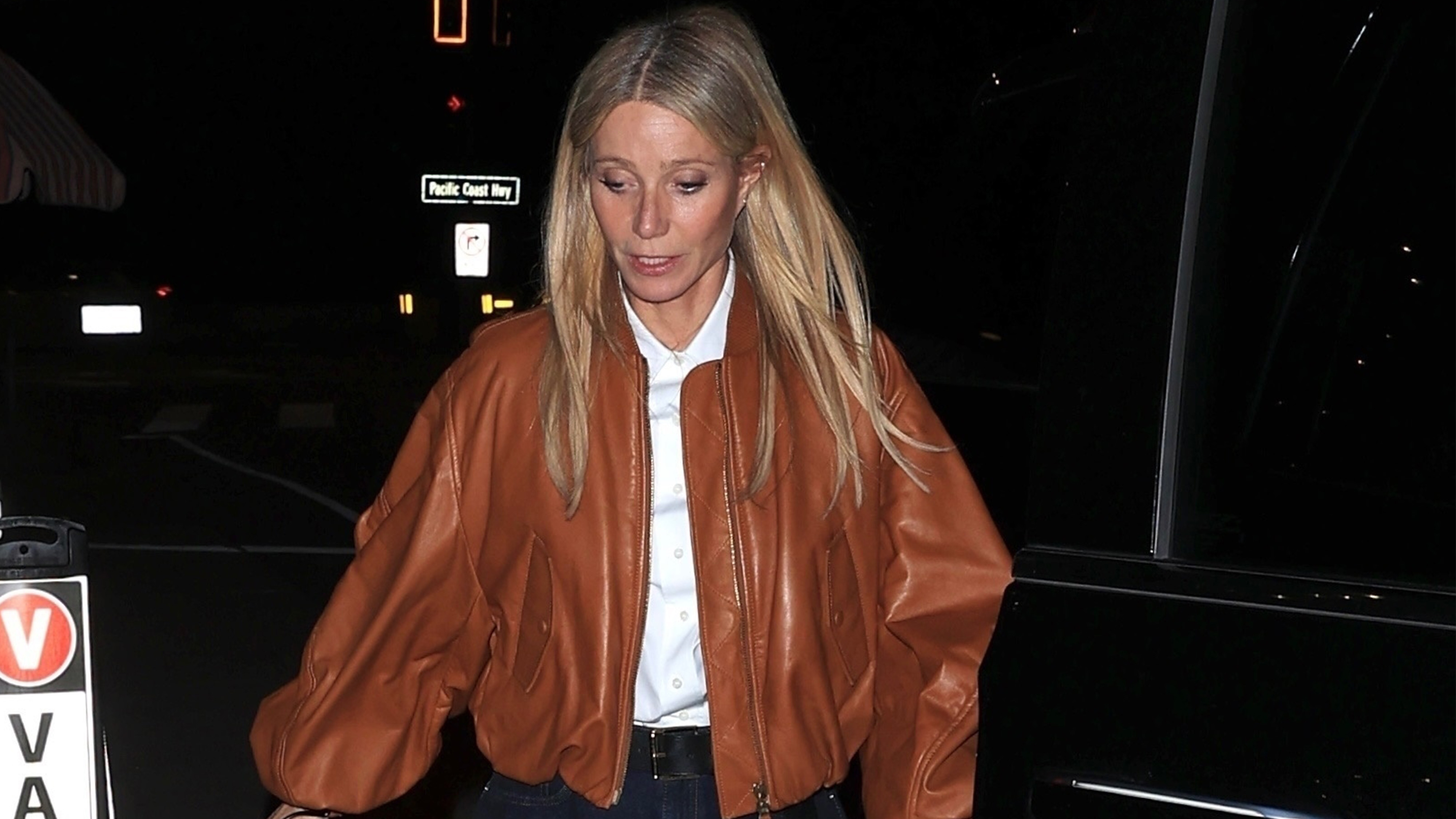 Gwyneth paltrow wears a tan leather jacket and white top with jeans.