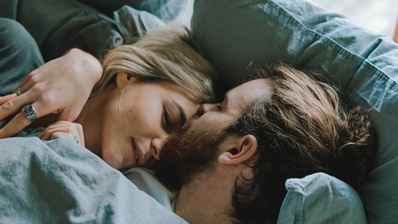 Man and woman cuddling up in bed, sleep &amp; wellness tips