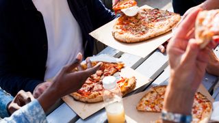 image shows a group of friends eating pizzas together