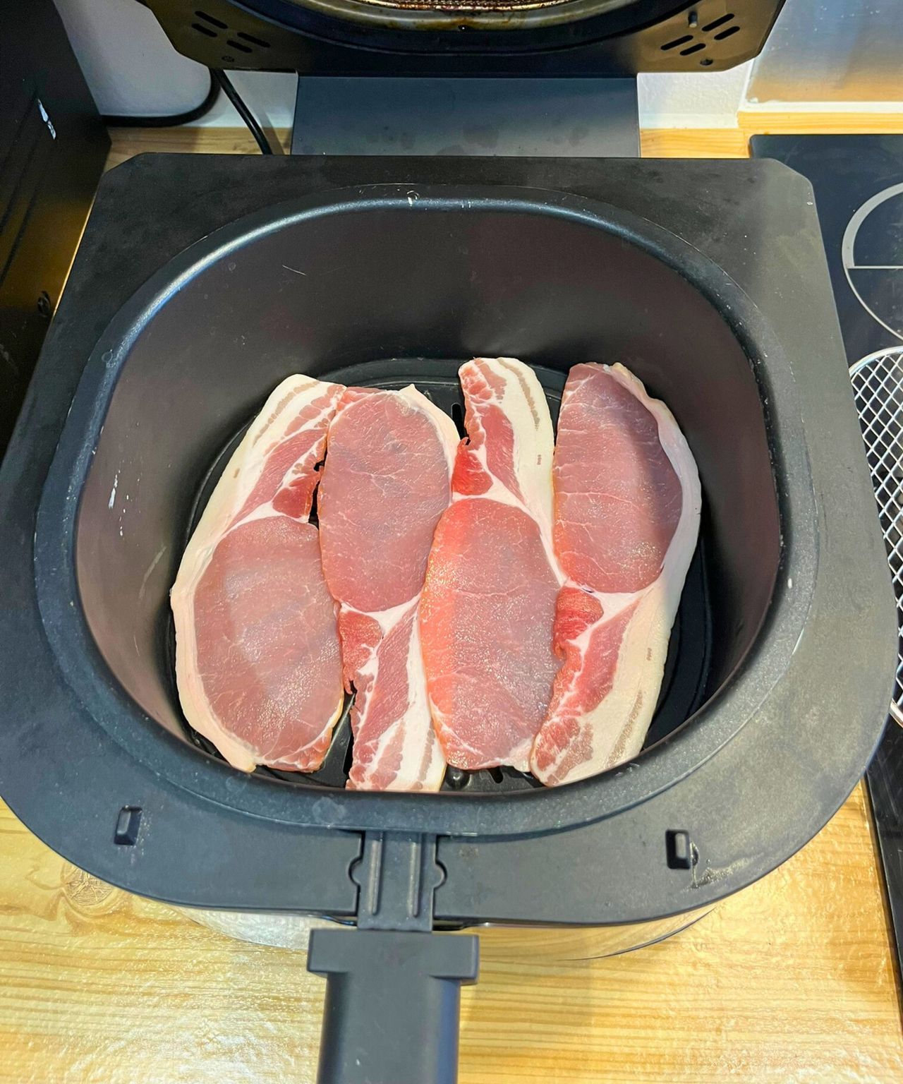 Raw bacon slices placed neatly across the bottom of my air fryer basket