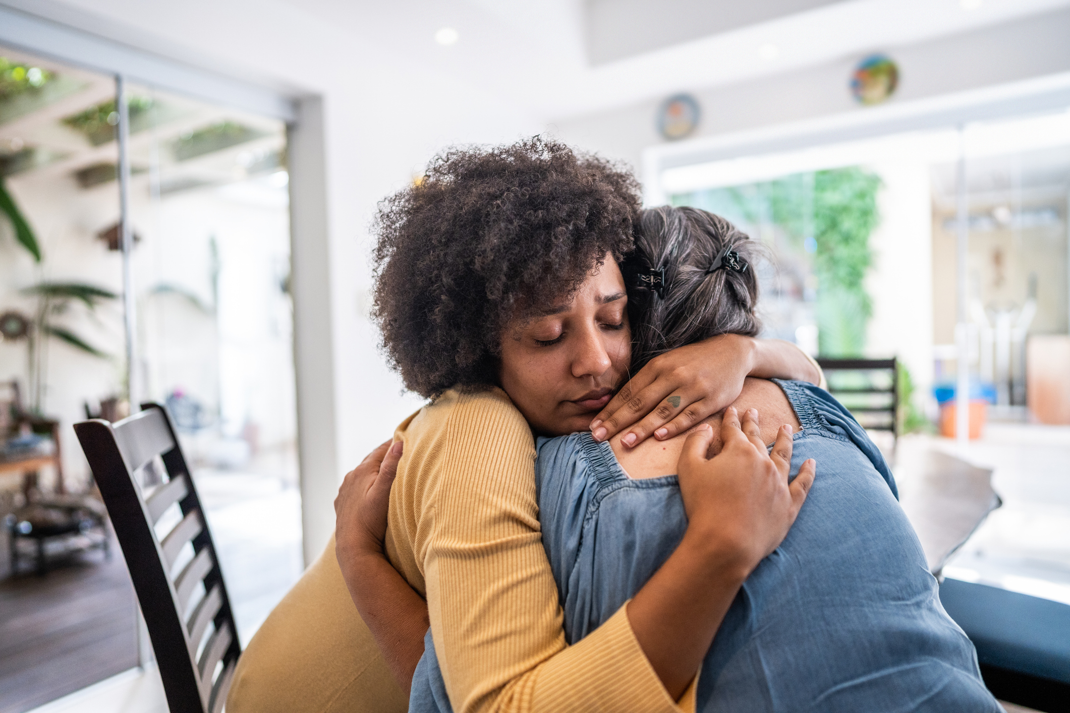 Sad young woman embracing her mother at home
