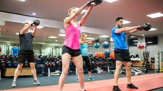 People perform kettlebell swing in gym