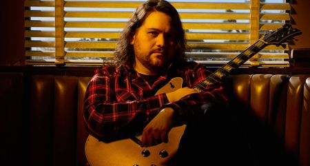 Wolfgang Van Halen pictured in warm lighting with his EVH signature semi-hollow