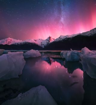 A photograph of the southern lights above mountains and an icy lake