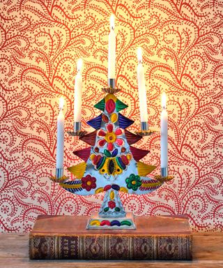 Christmas tree candle holder with red patterned wallpaper in background