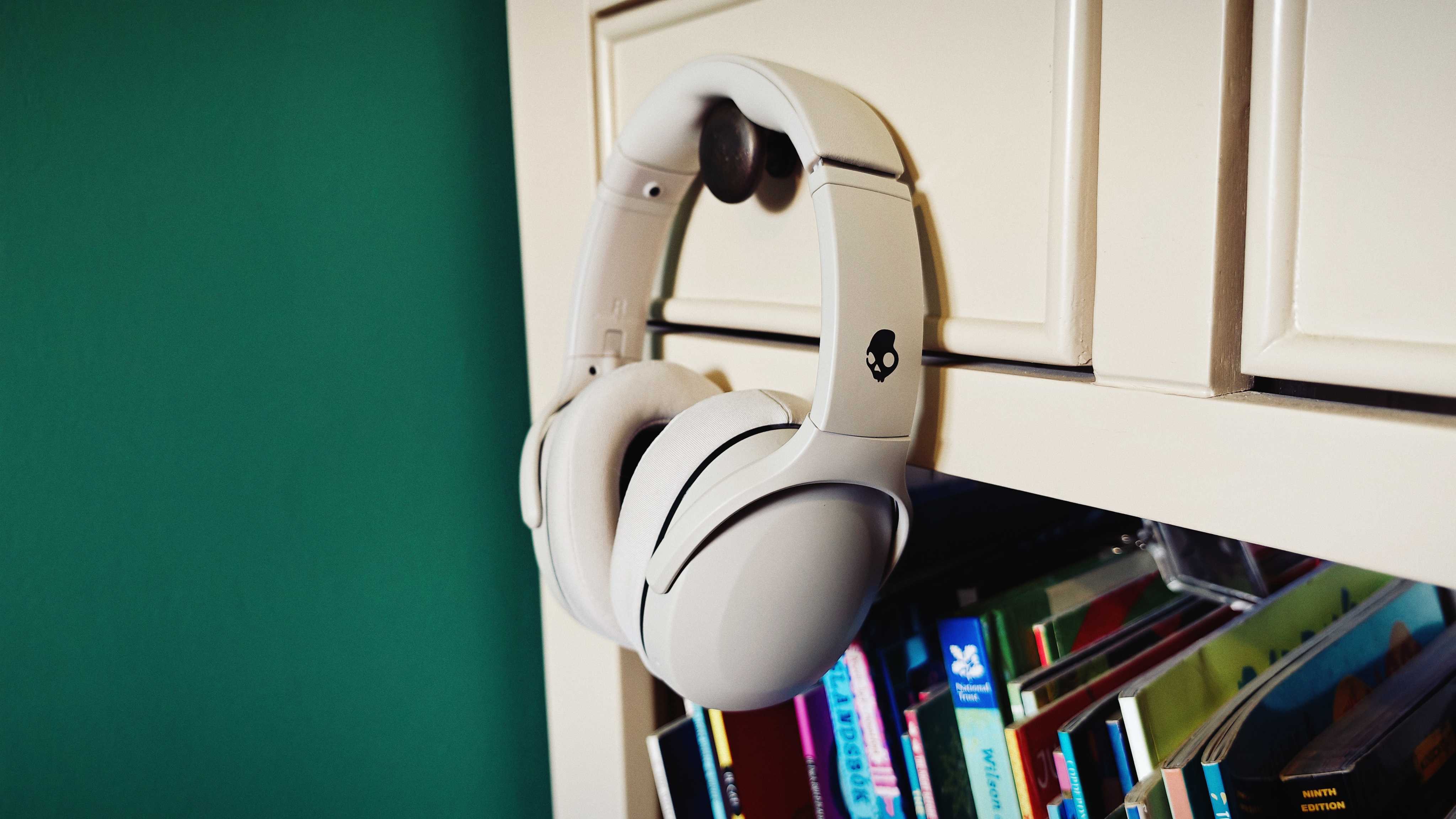A white pair of Skullcandy Crusher 540 Active headphones on a green sofa