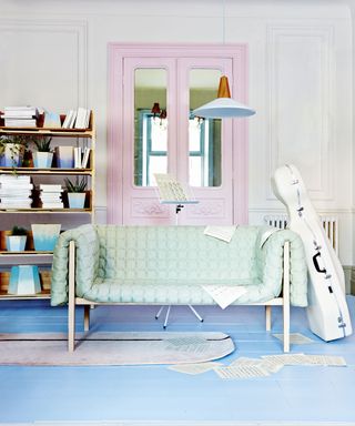 white wall pink door blue wooden floor book shelve and sofa