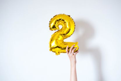 Holding an inflatable number 2 gold-colored balloon on a white background, 02/22/22 meme