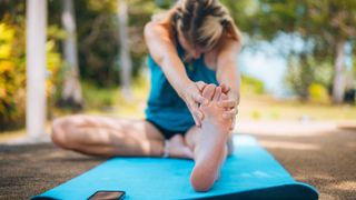 Woman stretching foot on yoga mat