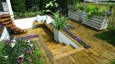 a lovely deck using one of the best decking stains, full of flowers, plants and garden furniture