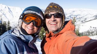 Smiling couple posing for selfie at ski resort