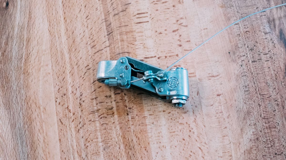 The silver body of a rear derailleur sits on a wooden table