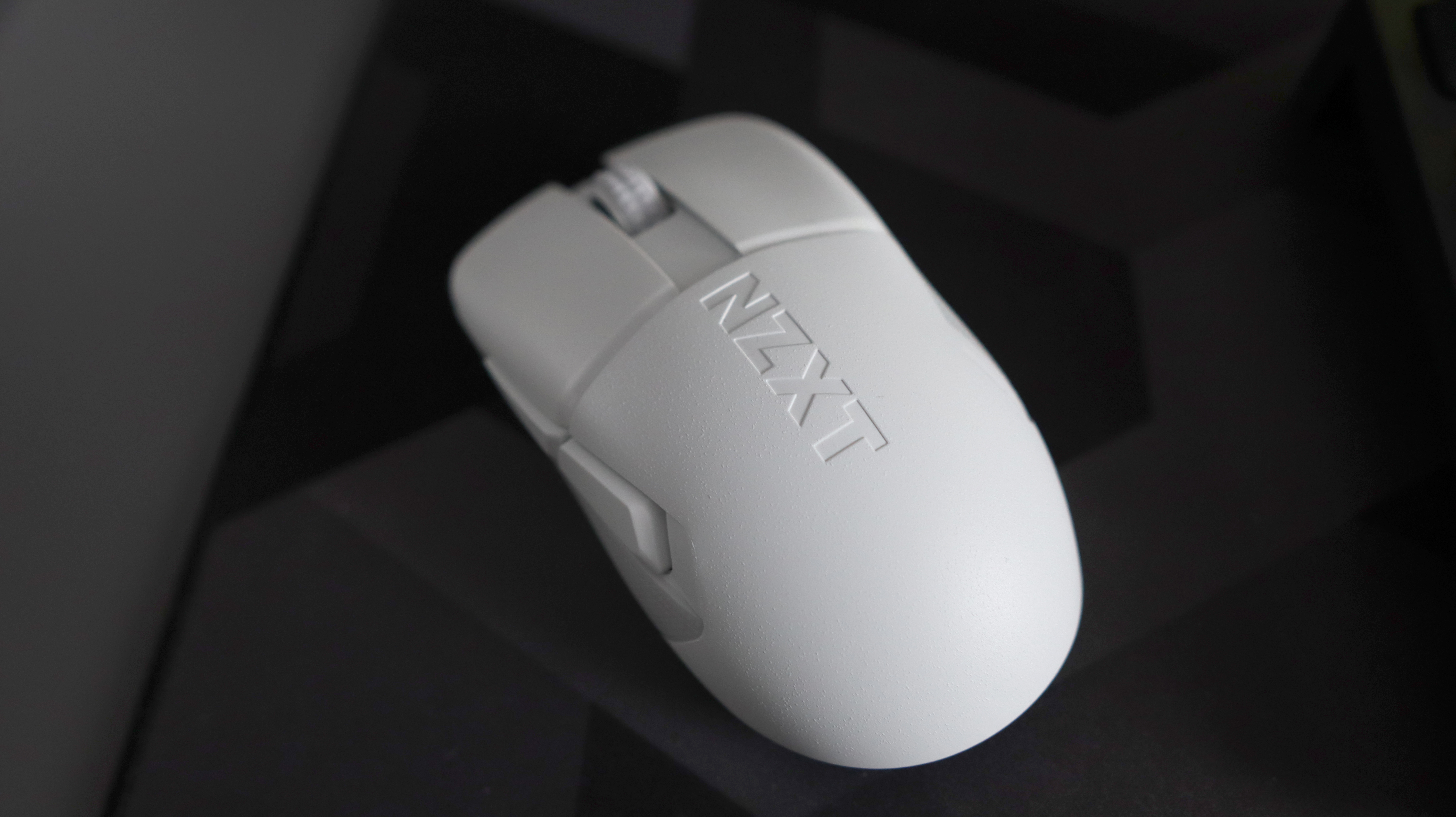 An NZXT Lift Elite Wireless gaming mouse in white set-up on a desk.