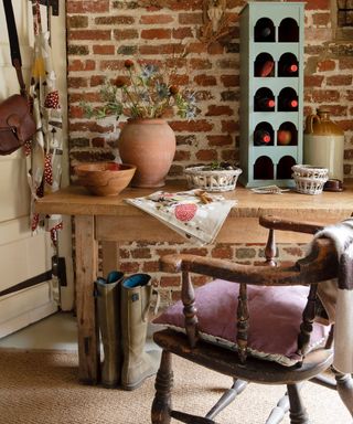 Storage ideas for sheds featuring a wooden table and chair, and duck egg blue wine rack in an exposed brick shed.