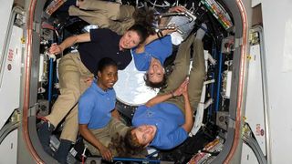 4 women in the international space station smiling at the camera