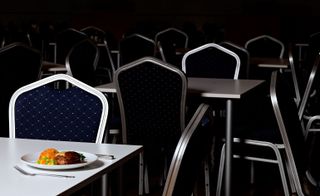 A plate of food sits on a table in an otherwise empty dining room