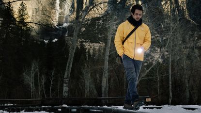 best torch: man walking in a forest holding a Maglite hand torch