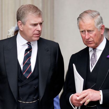 King Charles and Prince Andrew wearing dark suits, ties and serious expressions 