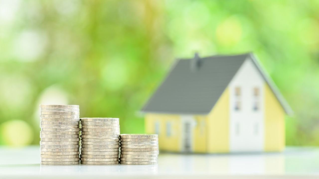 Pile of coins in front of model of a house