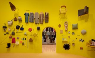 A yellow wall is adorned with clothes and accessories