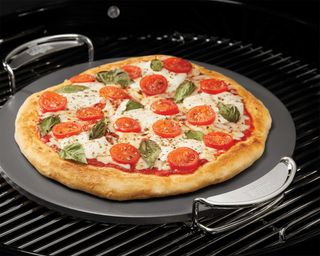 pizza being cooked on a pizza stone on a BBQ