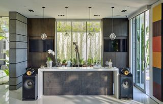 A home bar with mosaic effect tiles decked by sound system speakers
