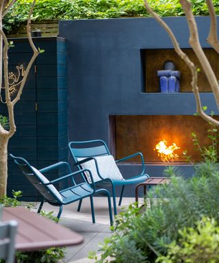 A fireplace in a garden built into a blue painted wall