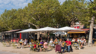 Diners eat under umbrellas at the outside tables of an Amsterdam café