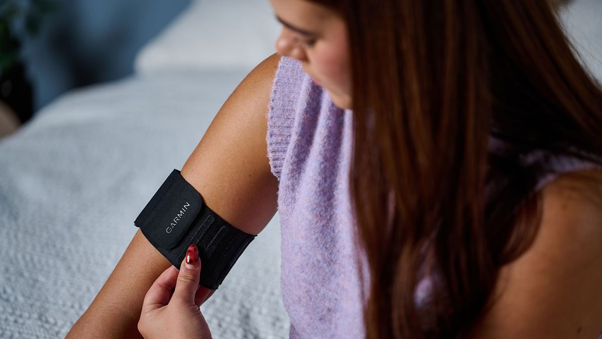 Tom's Guide's sleep tech tester wearing a purple top placing the Garmin Index Sleep Monitor on right upper arm