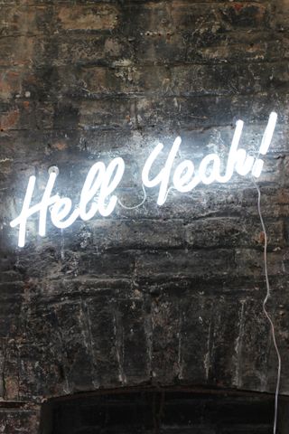Neon Hell Yeah light from Rockett St George on an exposed brick wall
