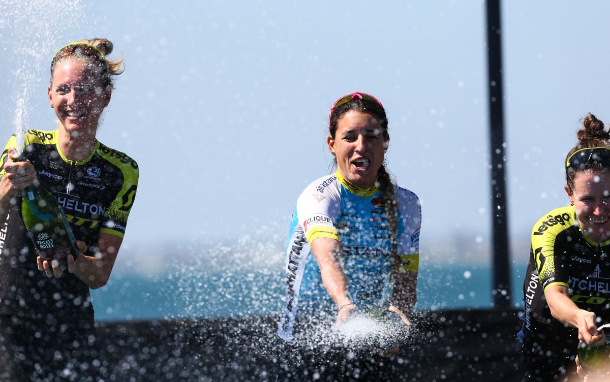 The riders spray the champagne on the podium